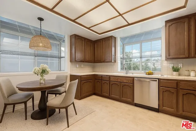 a kitchen with stainless steel appliances granite countertop a sink a stove cabinets dining table and chairs