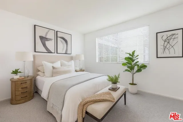 a bedroom with a bed a couch and a potted plant