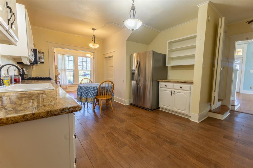 1115 Austin Street Coleman, TX 76834 - Photo 11 of 40 a kitchen with stainless steel appliances granite countertop sink stove refrigerator and wooden floor