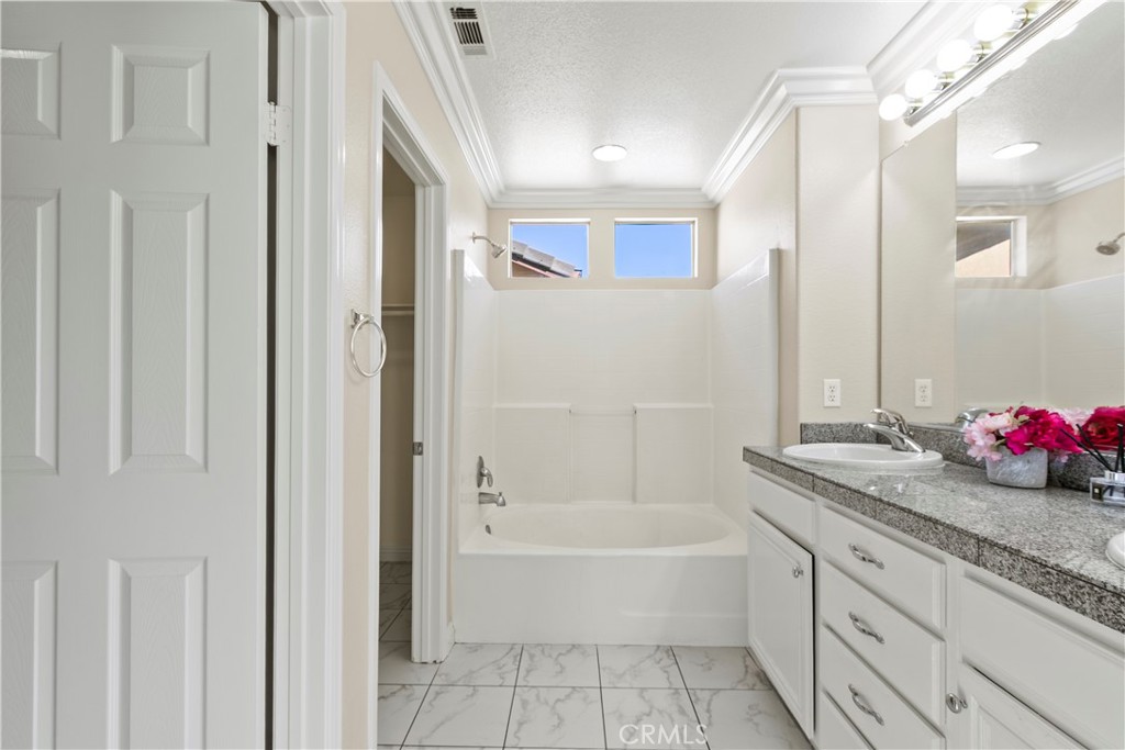 6837 Cosmos Street Chino, CA 91710 - Photo 21 of 36 a bathroom with a granite countertop tub sink and mirror