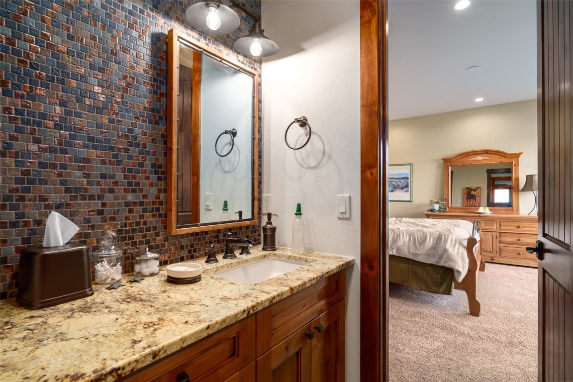 28100 Columbine Ridge Road Steamboat Springs, CO 80487 - Photo 30 of 43 a en suite bathroom with a granite countertop sink and a mirror