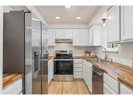 a kitchen with stainless steel appliances granite countertop white cabinets and a sink