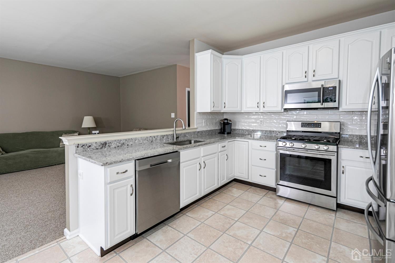 30 Aster Way Dayton, NJ 08810 - Photo 11 of 38 a kitchen with granite countertop white cabinets and white appliances
