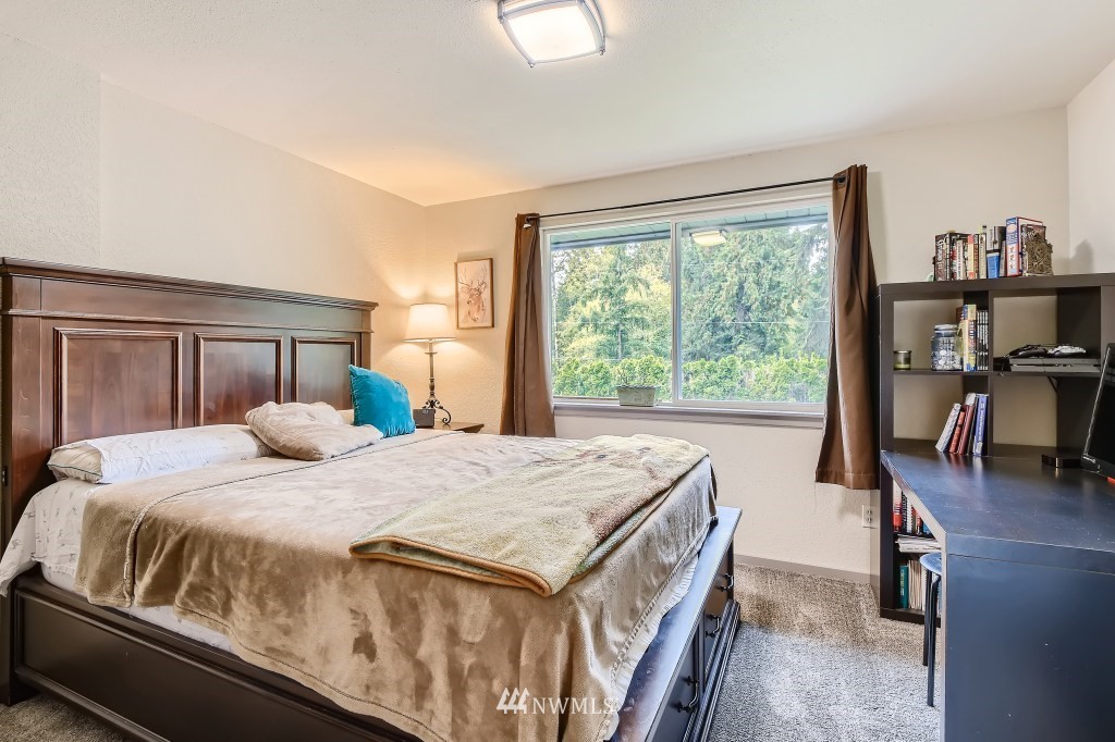 22420 61st Avenue Southeast Bothell, WA 98021 - Photo 17 of 39 a bedroom with a bed and a flat tv screen next to a window
