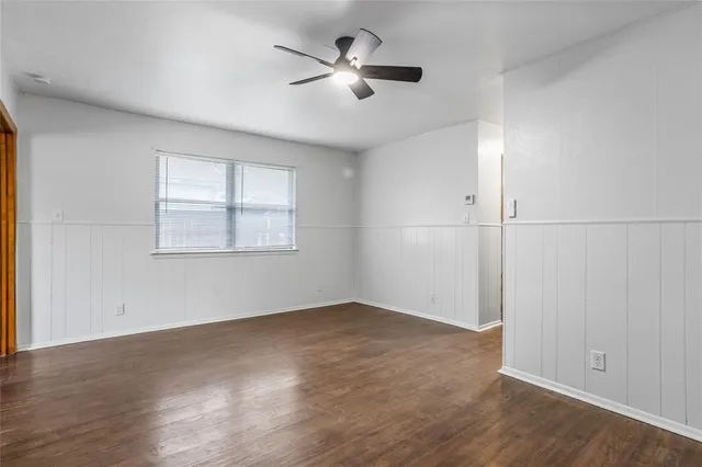 an empty room with wooden floor ceiling fan and windows