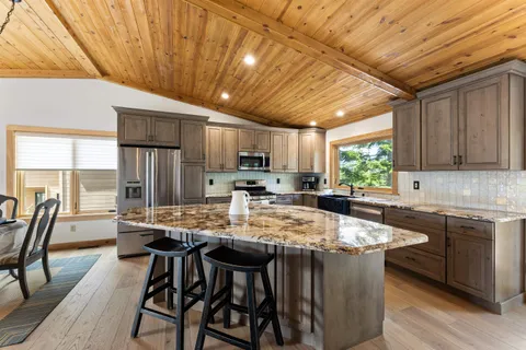 a kitchen with stainless steel appliances granite countertop a stove a sink dishwasher a stove a refrigerator with a dining table and chairs