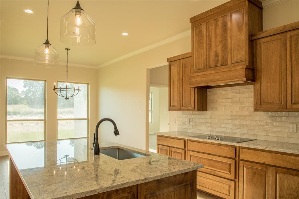 141 Prairie Winds Drive Poolville, TX 76487 - Photo 11 of 15 a kitchen with kitchen island a counter top a stove a sink and living area view