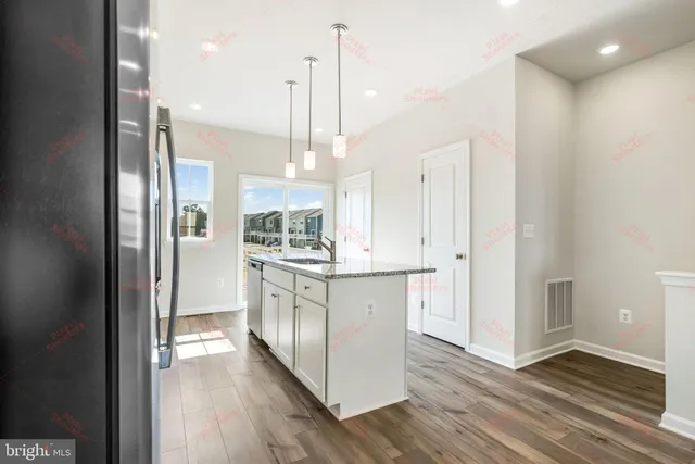 a kitchen with stainless steel appliances granite countertop a refrigerator a sink and wooden floors