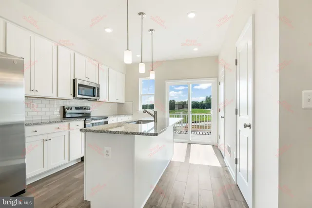 a kitchen with stainless steel appliances granite countertop a refrigerator a sink dishwasher a stove and white cabinets with wooden floor