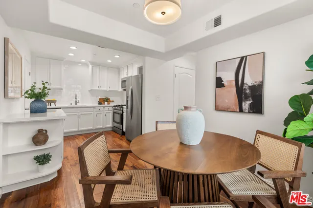 a kitchen with stainless steel appliances a dining table chairs and window