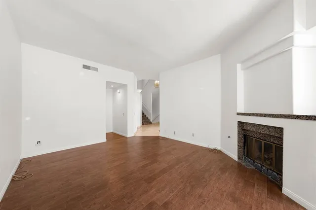 a view of empty room with wooden floor and fireplace