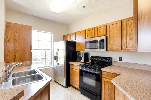 a kitchen that has a sink wooden floor and stainless steel appliances