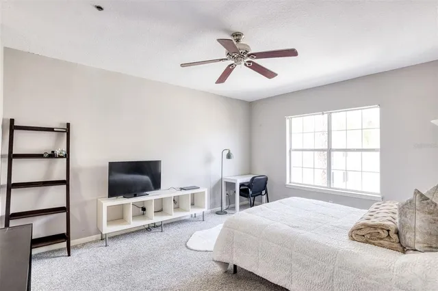 a bedroom with a bed flat screen tv and a window