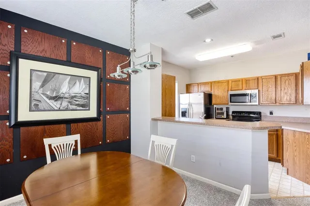 a living room with stainless steel appliances a couch a dining table and chairs