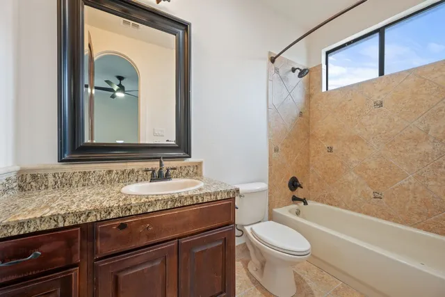 a bathroom with a granite countertop toilet sink and mirror