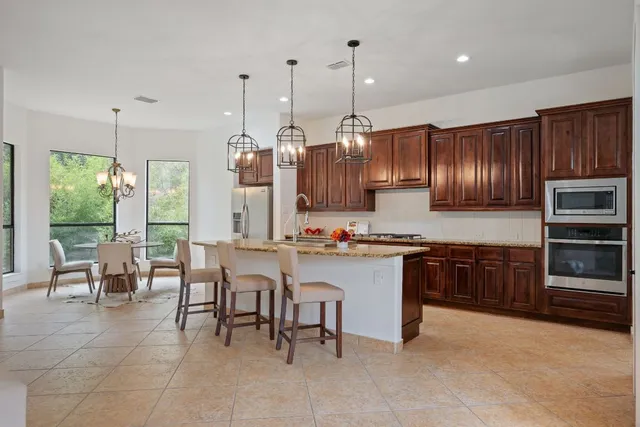 a kitchen with stainless steel appliances granite countertop wooden cabinets a stove a sink and a view