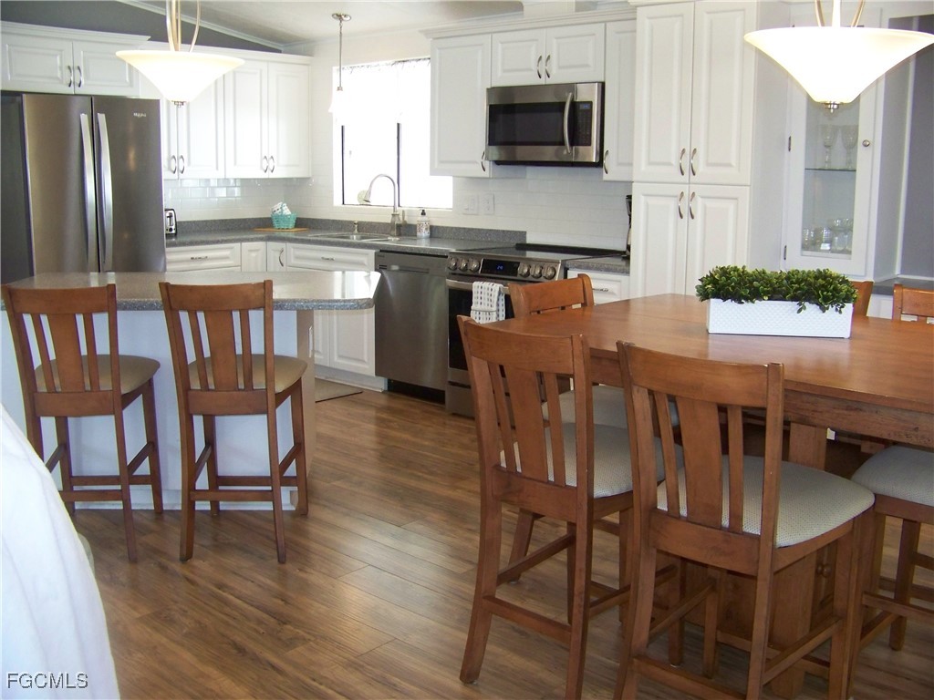 15550 Burnt Store Road, Unit 62 Punta Gorda, FL 33955 - Photo 19 of 50 a kitchen with stainless steel appliances granite countertop a dining table chairs refrigerator sink and cabinets
