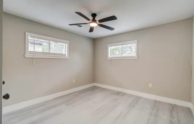 an empty room with ceiling fan and window