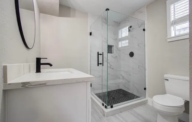 a bathroom with a granite countertop sink a toilet and shower