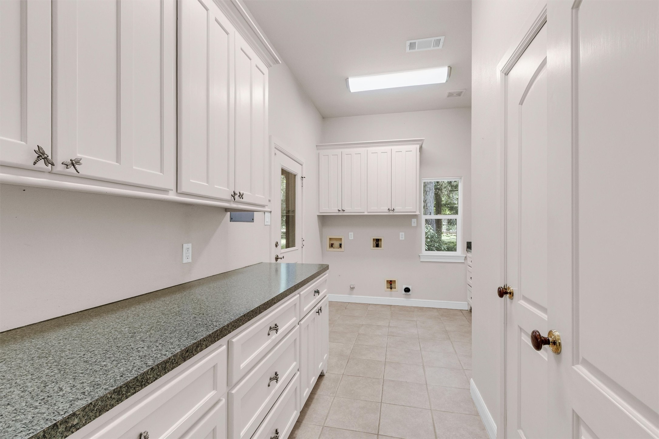 10331 Iron Ore Road Conroe, TX 77303 - Photo 26 of 47 Spacious laundry room with more cabinetry and household storage, utility sink, sleek countertops, and natural light from a large window, perfect for efficient household chores.