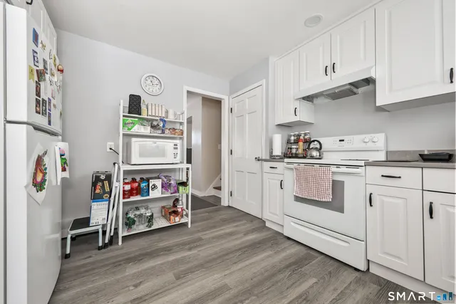 a kitchen with stainless steel appliances white cabinets and wooden floor