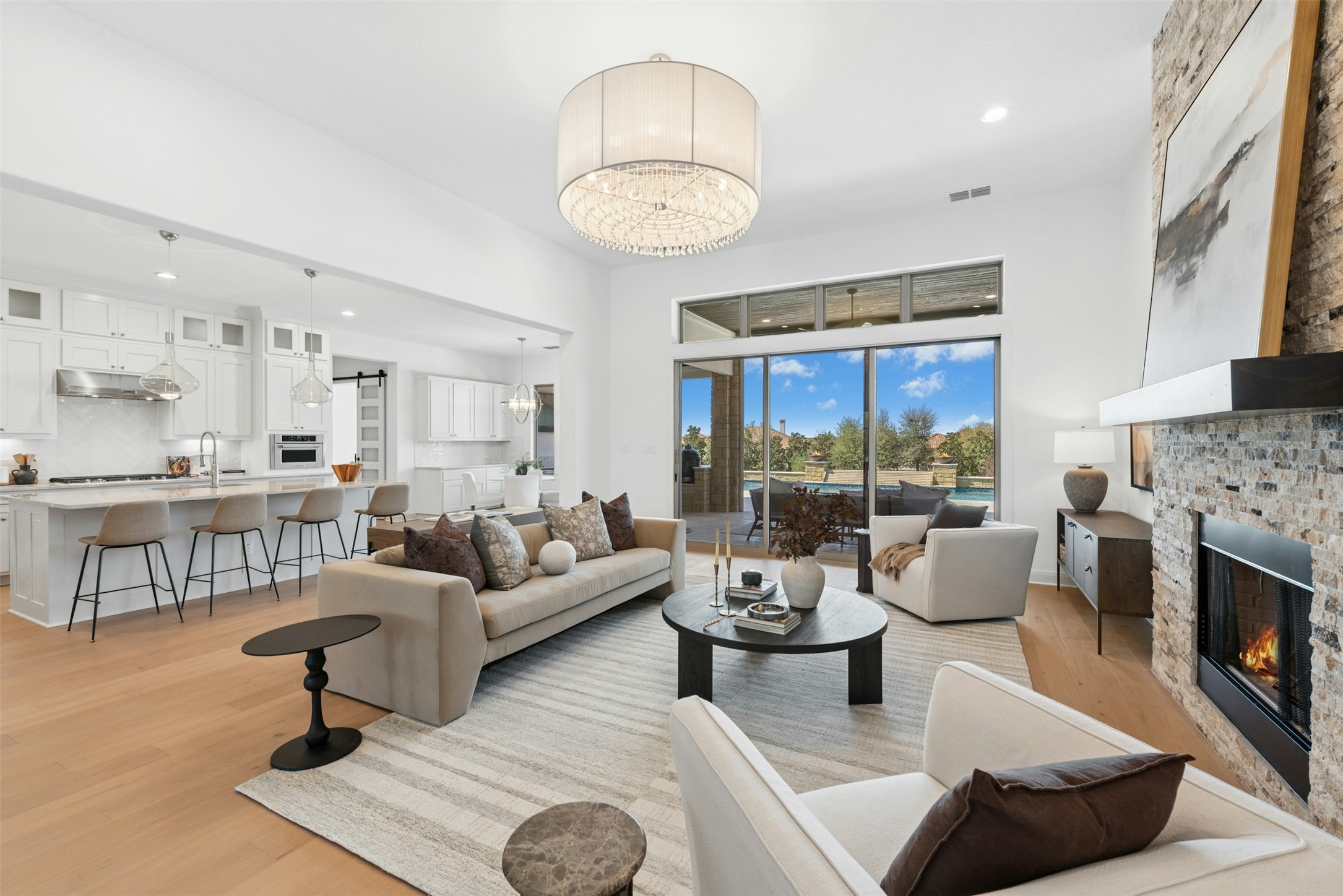 401 Brave Face Street Leander, TX 78641 - Photo 5 of 35 Living room with a brick fireplace, light wood finished floors, a chandelier, and a high ceiling