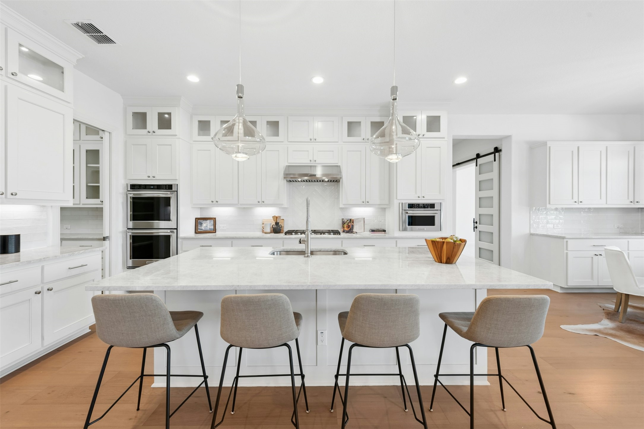 401 Brave Face Street Leander, TX 78641 - Photo 9 of 35 Kitchen with a barn door, light stone counters, tasteful backsplash, and light wood-style floors