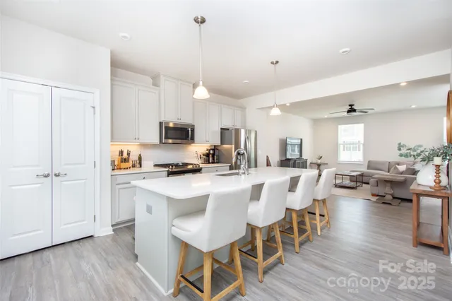 a kitchen with stainless steel appliances a dining table chairs stove a refrigerator and cabinets