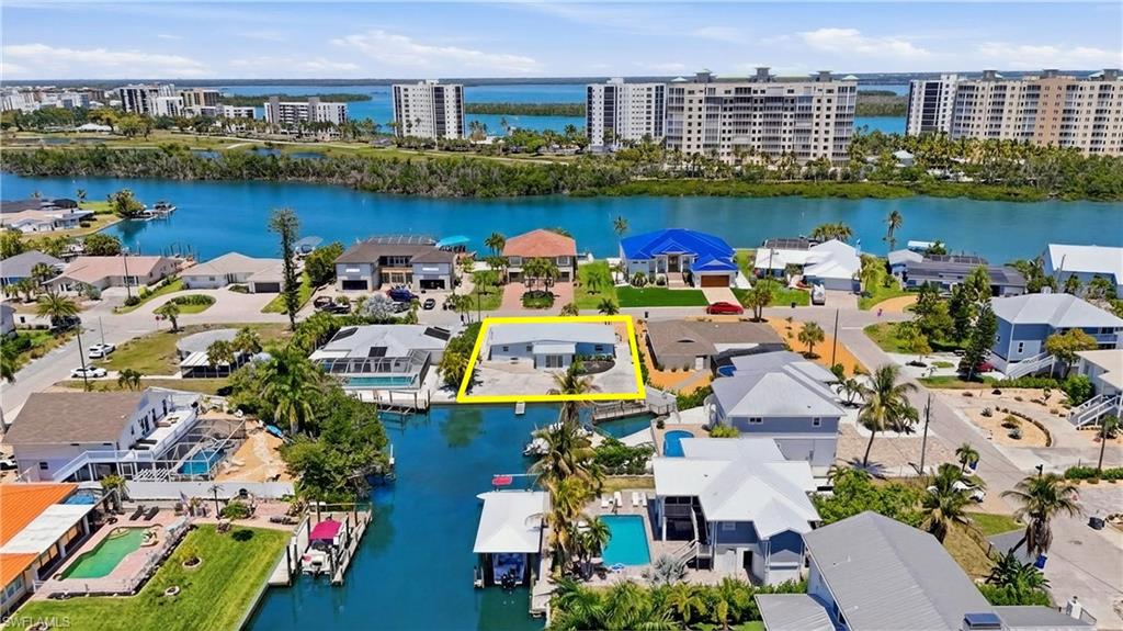 Waterfront property featuring a private boat dock, a paved driveway, and mature landscaping - Virtually Edited Image