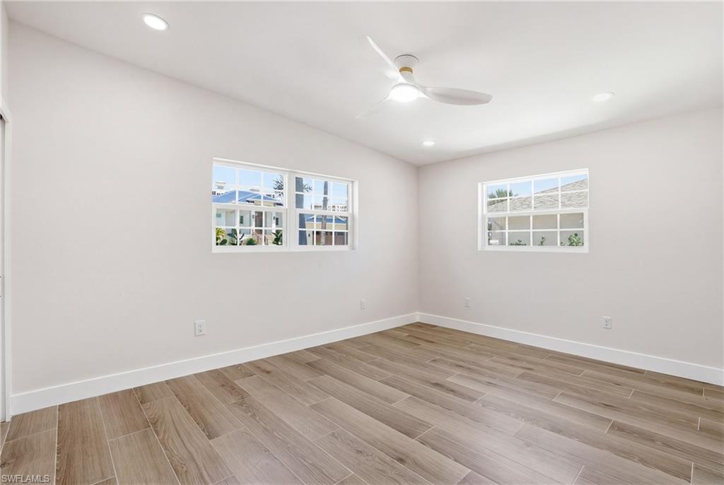 8336 Lagoon Road Fort Myers Beach, FL 33931 - Photo 13 of 50 This room features wood-look tile flooring, white walls, and recessed lighting - Virtually Edited Image