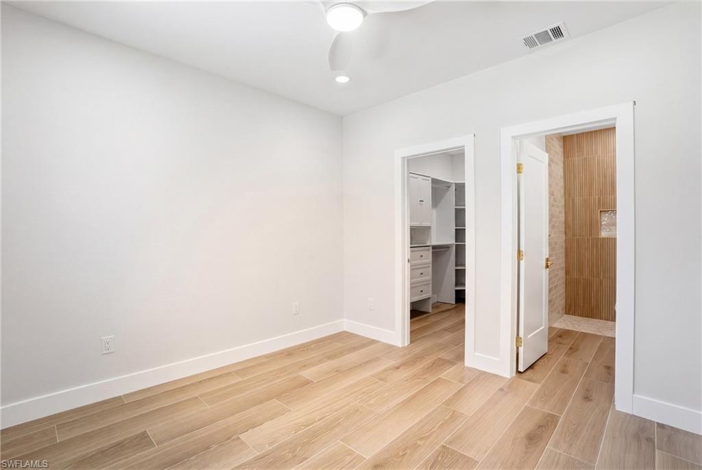 8336 Lagoon Road Fort Myers Beach, FL 33931 - Photo 16 of 50 The room features light-colored wood flooring, white walls, and a ceiling fan with integrated lighting - Virtually Edited Image