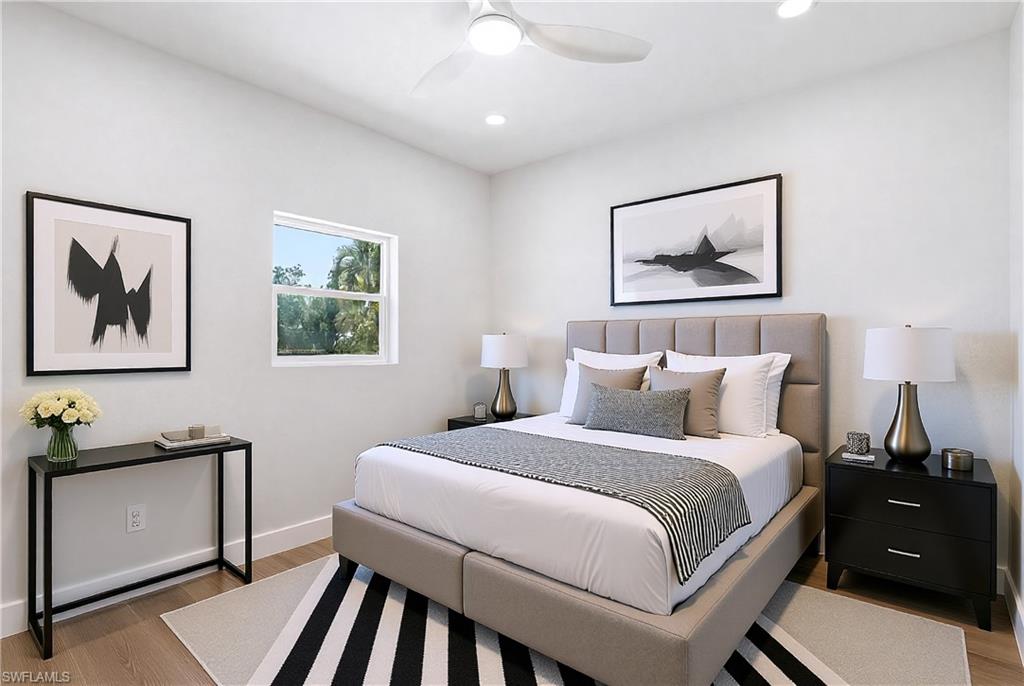 8336 Lagoon Road Fort Myers Beach, FL 33931 - Photo 20 of 50 The bedroom features light wood flooring, a window providing views of greenery, and a ceiling fan with integrated lighting - Virtually Edited Image
