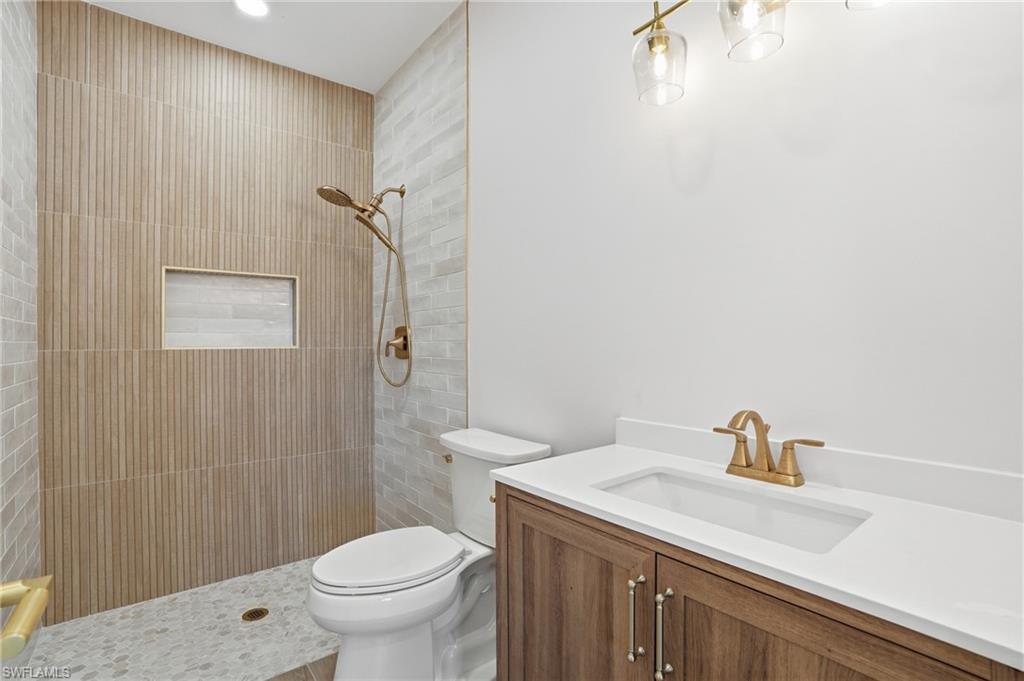 8336 Lagoon Road Fort Myers Beach, FL 33931 - Photo 22 of 50 The bathroom features a walk-in shower with textured wall tiles, a recessed shower shelf, and a gold-toned shower fixture - Virtually Edited Image