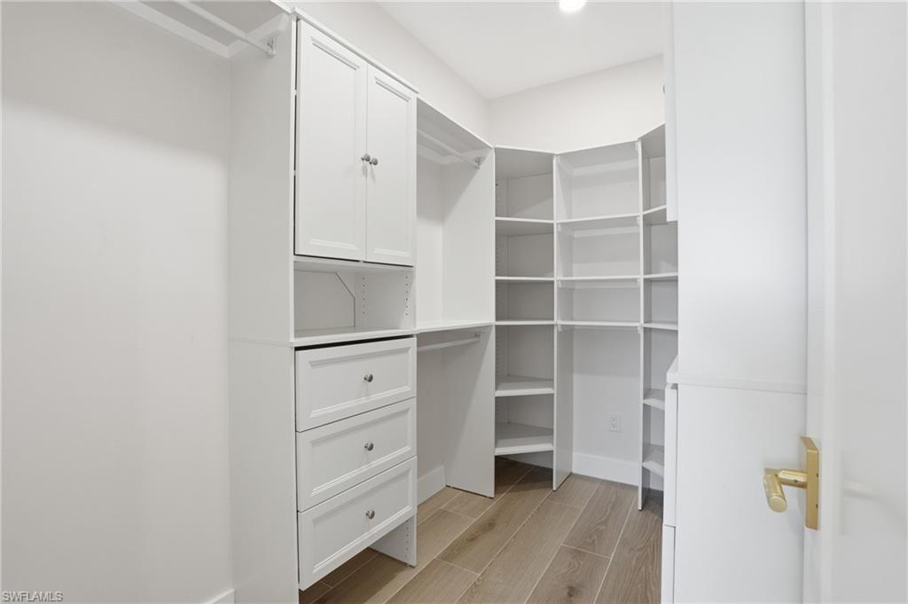 8336 Lagoon Road Fort Myers Beach, FL 33931 - Photo 23 of 50 Custom closet featuring white cabinetry, drawers with silver-toned hardware, and extensive shelving - Virtually Edited Image