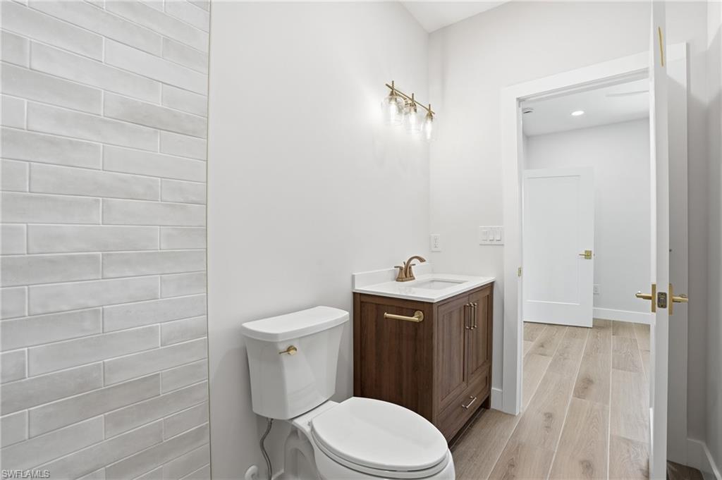 8336 Lagoon Road Fort Myers Beach, FL 33931 - Photo 24 of 50 The bathroom features a toilet with a brass flush lever, a vanity with a dark wood cabinet and white countertop, and a brass faucet - Virtually Edited Image