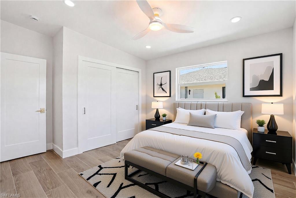 8336 Lagoon Road Fort Myers Beach, FL 33931 - Photo 27 of 50 This bedroom features light wood-look flooring, a window providing natural light, and a ceiling fan with integrated lighting - Virtually Edited Image