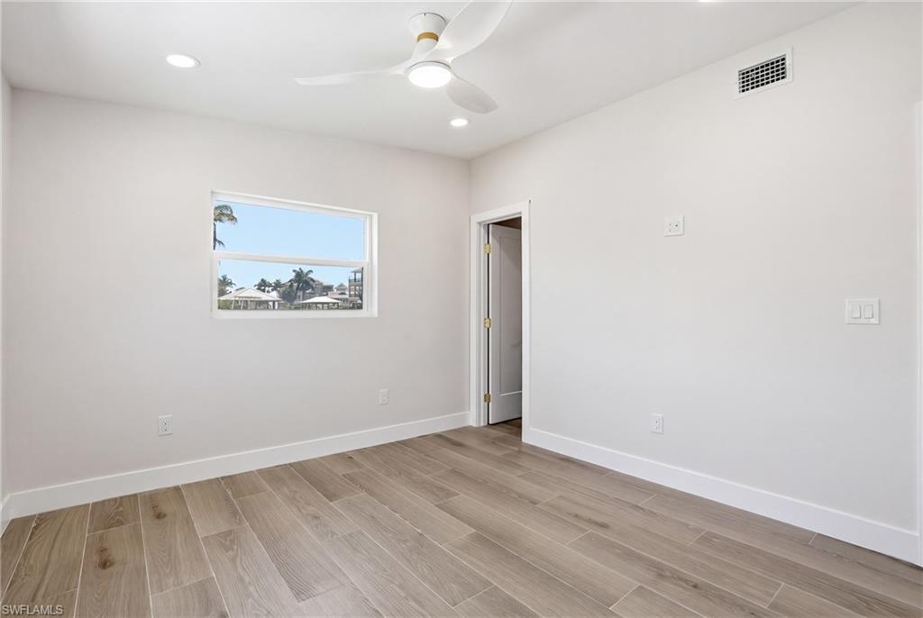 8336 Lagoon Road Fort Myers Beach, FL 33931 - Photo 28 of 50 This room features light wood-look flooring, a window with a water view, and a ceiling fan with integrated lighting - Virtually Edited Image