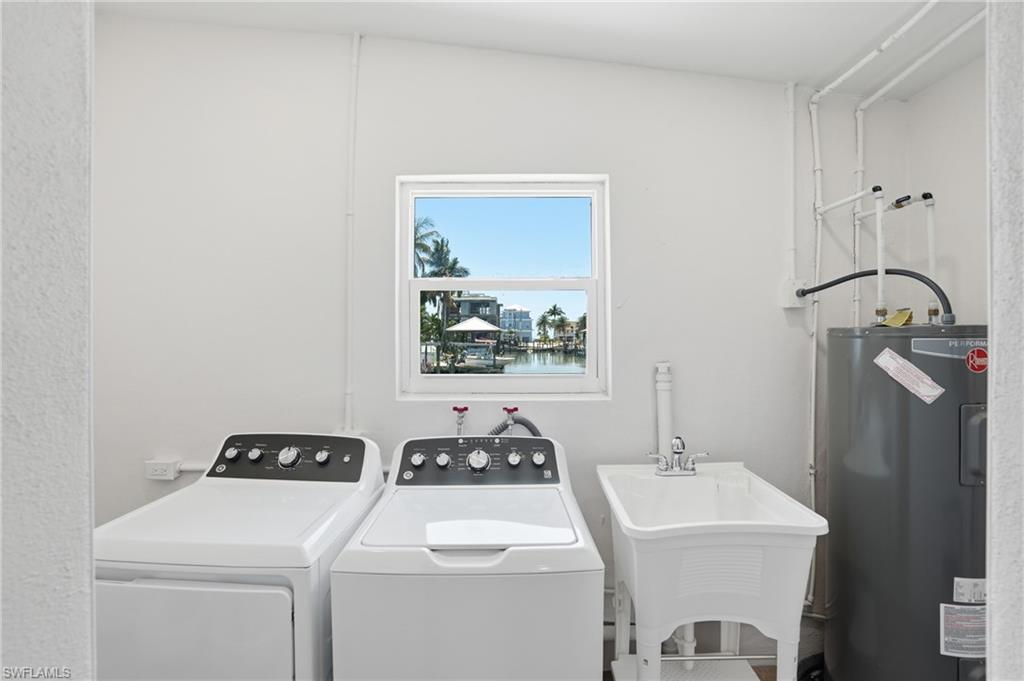 8336 Lagoon Road Fort Myers Beach, FL 33931 - Photo 29 of 50 Utility room featuring a window with a water view, a laundry sink, and a water heater - Virtually Edited Image