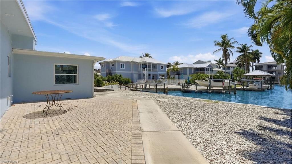 8336 Lagoon Road Fort Myers Beach, FL 33931 - Photo 36 of 50 The property features a paved patio area and a waterfront setting with docks - Virtually Edited Image