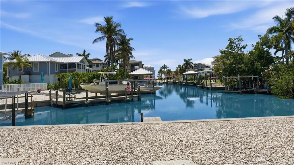 8336 Lagoon Road Fort Myers Beach, FL 33931 - Photo 37 of 50 Waterfront property with private boat dock and lift, surrounded by tropical landscaping and palm trees - Virtually Edited Image