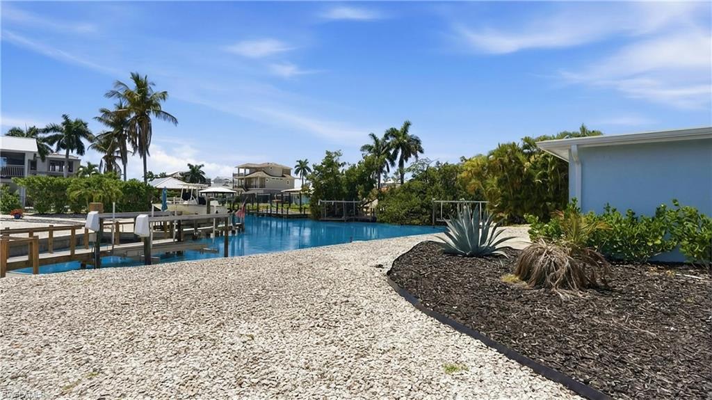 8336 Lagoon Road Fort Myers Beach, FL 33931 - Photo 38 of 50 The property features a private dock with direct canal access, surrounded by lush landscaping and palm trees - Virtually Edited Image