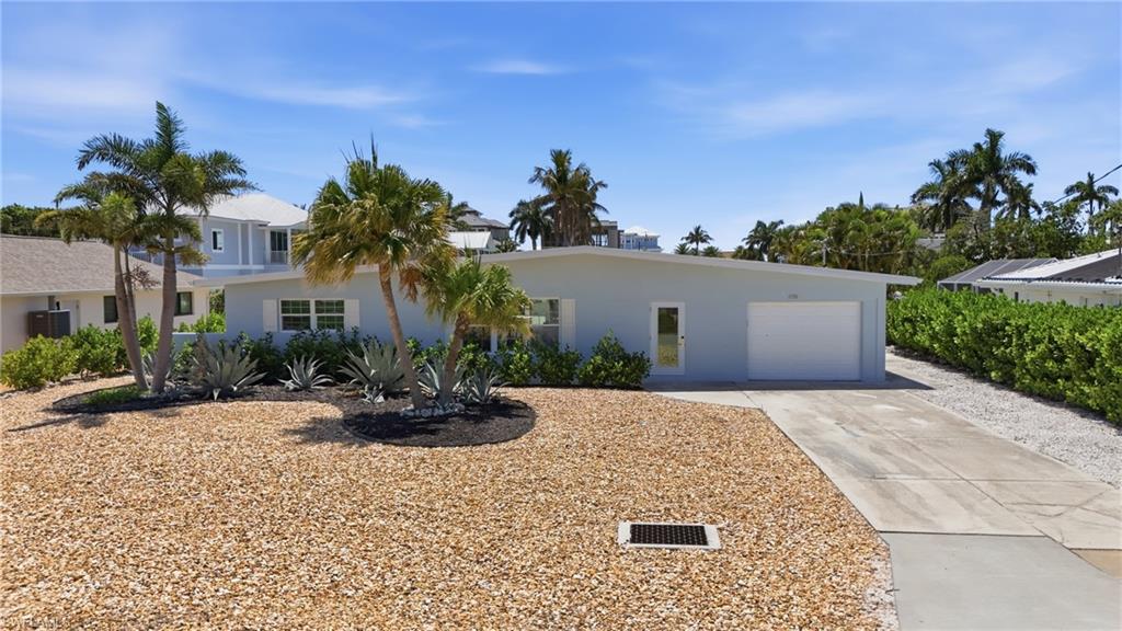8336 Lagoon Road Fort Myers Beach, FL 33931 - Photo 45 of 50 The property features a light-colored exterior, a garage with a white door, and a paved driveway - Virtually Edited Image