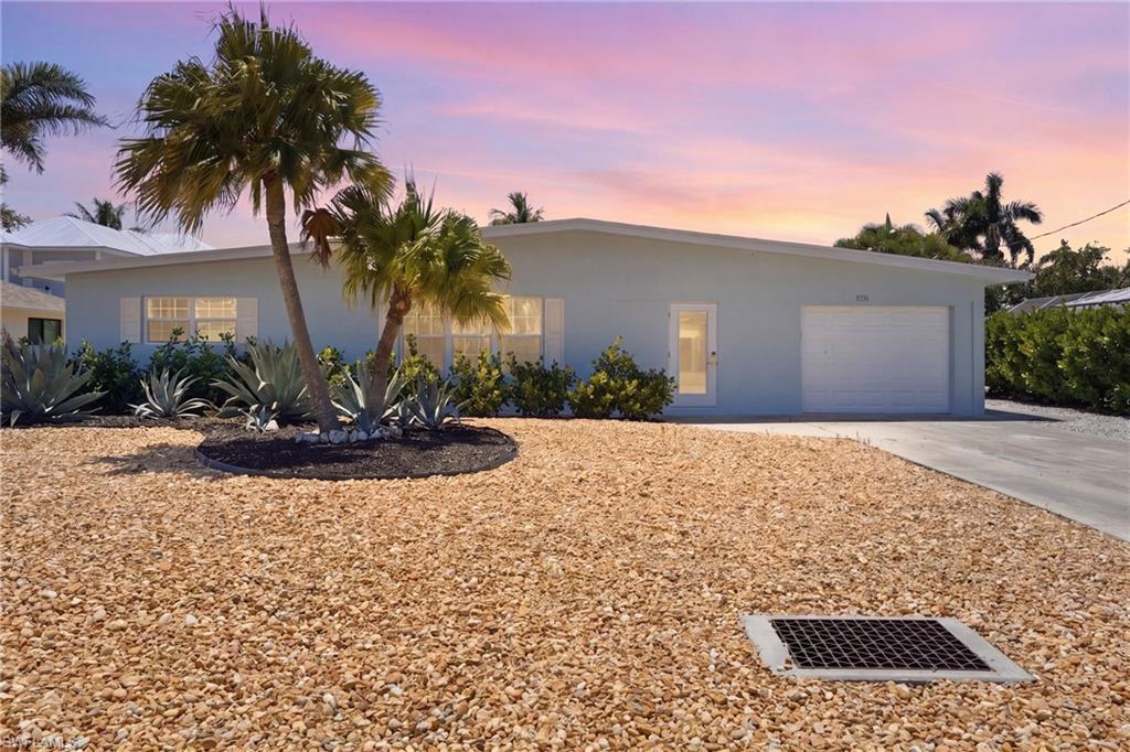 8336 Lagoon Road Fort Myers Beach, FL 33931 - Photo 50 of 50 The property features a light blue exterior, a white garage door, and a well-maintained gravel yard - Virtually Edited Image