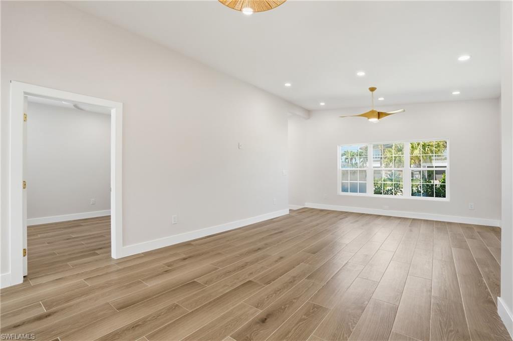 8336 Lagoon Road Fort Myers Beach, FL 33931 - Photo 7 of 50 Spacious room featuring light wood-style flooring, white walls, and a contemporary ceiling fan - Virtually Edited Image