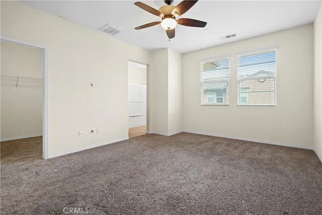 an empty room with windows and fan