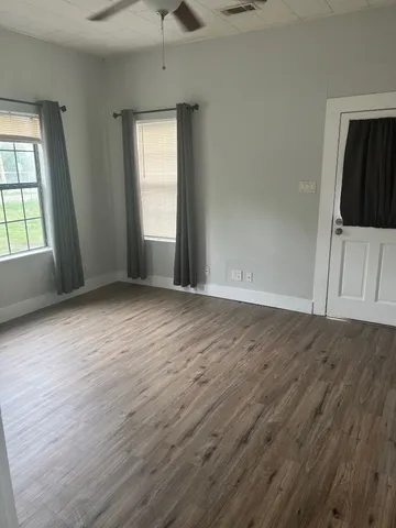 an empty room with wooden floor and windows