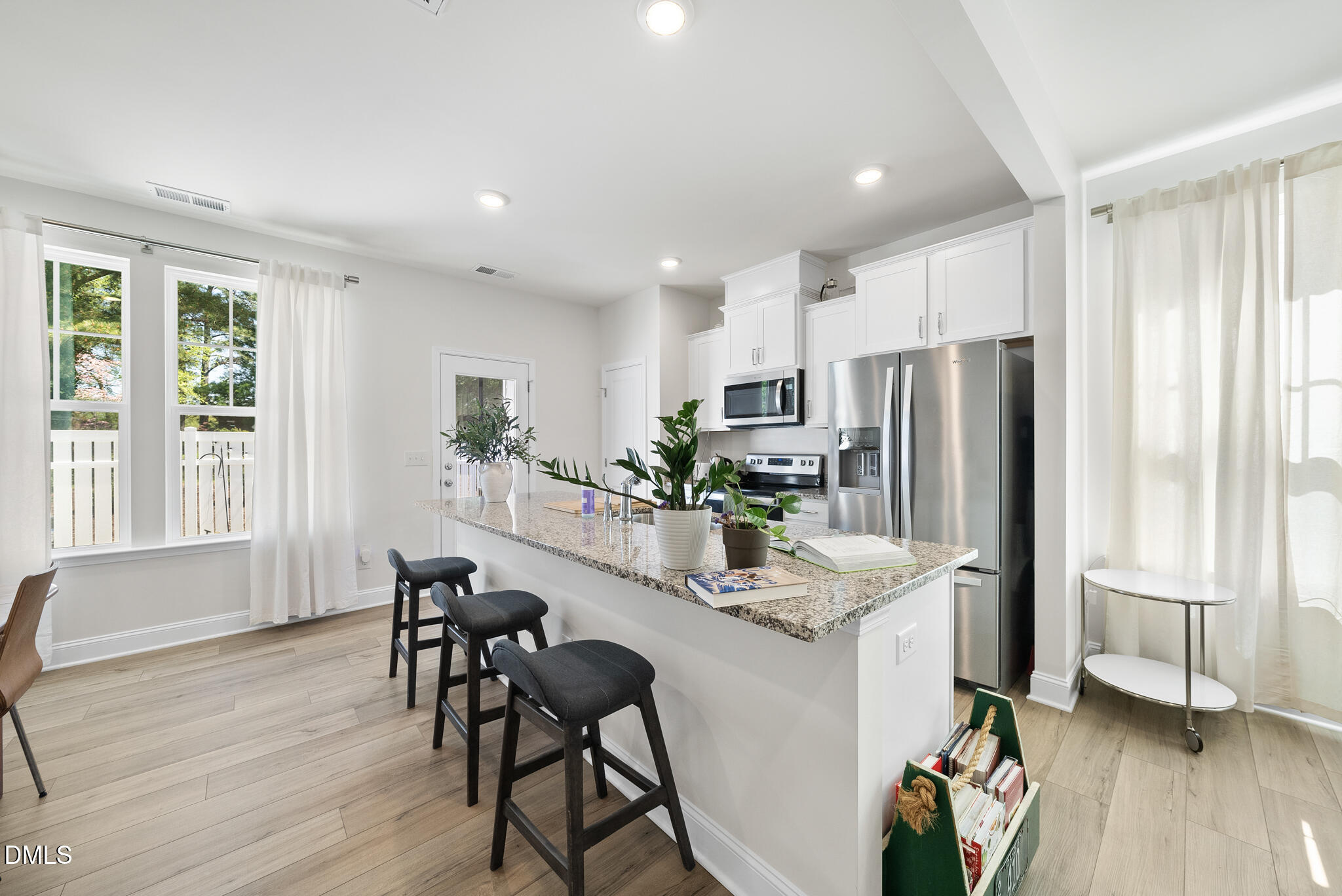 53 Bibury Way Angier, NC 27501 - Photo 11 of 50 a kitchen with stainless steel appliances a refrigerator a stove a dining table and chairs with wooden floor