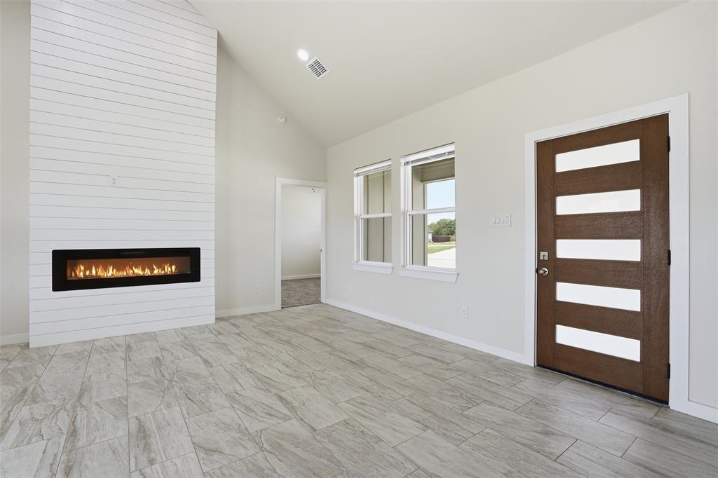 532 Highview Court Godley, TX 76044 - Photo 34 of 39 Living area featuring a floor-to-ceiling shiplap fireplace with a linear insert, vaulted ceiling, and wood-look tile flooring