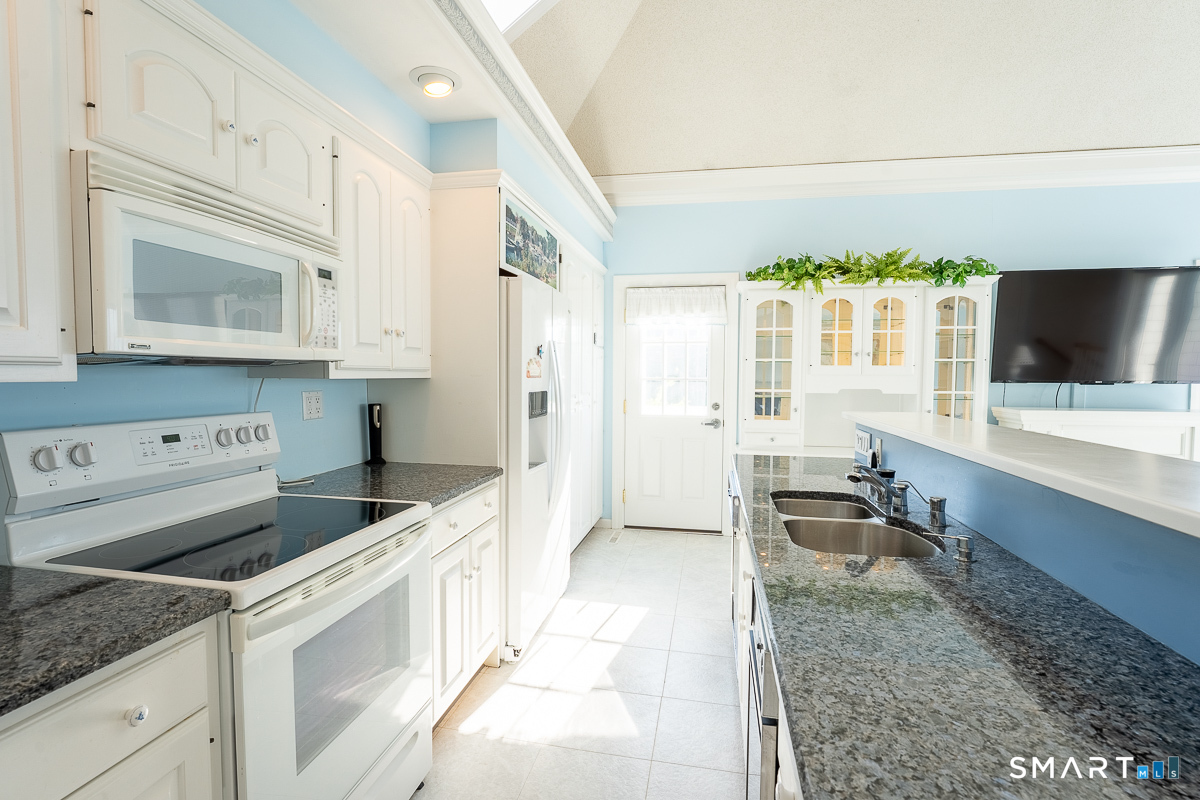 132 Latimer Point Road, Unit 132 Stonington, CT 06378 - Photo 15 of 38 Kitchen with granite counters, stainless appliances including Whirlpool side-by-side refrigerator, dishwasher and trash compactor.