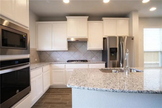 a kitchen with kitchen island granite countertop a sink cabinets and stainless steel appliances